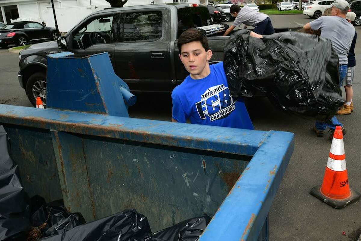 Tood Woodring, 13, heaves a bag of garbage into the Dumpster during the cleanup.