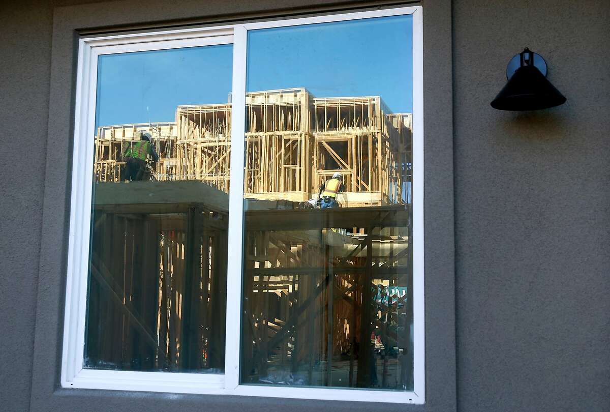 Framework of a residential building under construction is reflected on the window of a unit nearing completion at the Ice House development by City Ventures in Oakland, Calif. on Thursday, June 27, 2019.