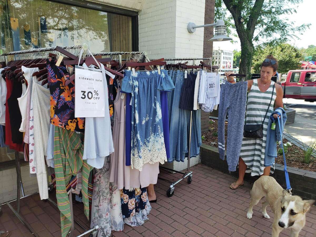 Westporter Nancy Lagnese, with dog Steve, checks out clothing at South Moon Under during the annual Westport Sidewalk Sale throughout Main Street, Post Road and areas surrounding downtown on June 28, 2019.