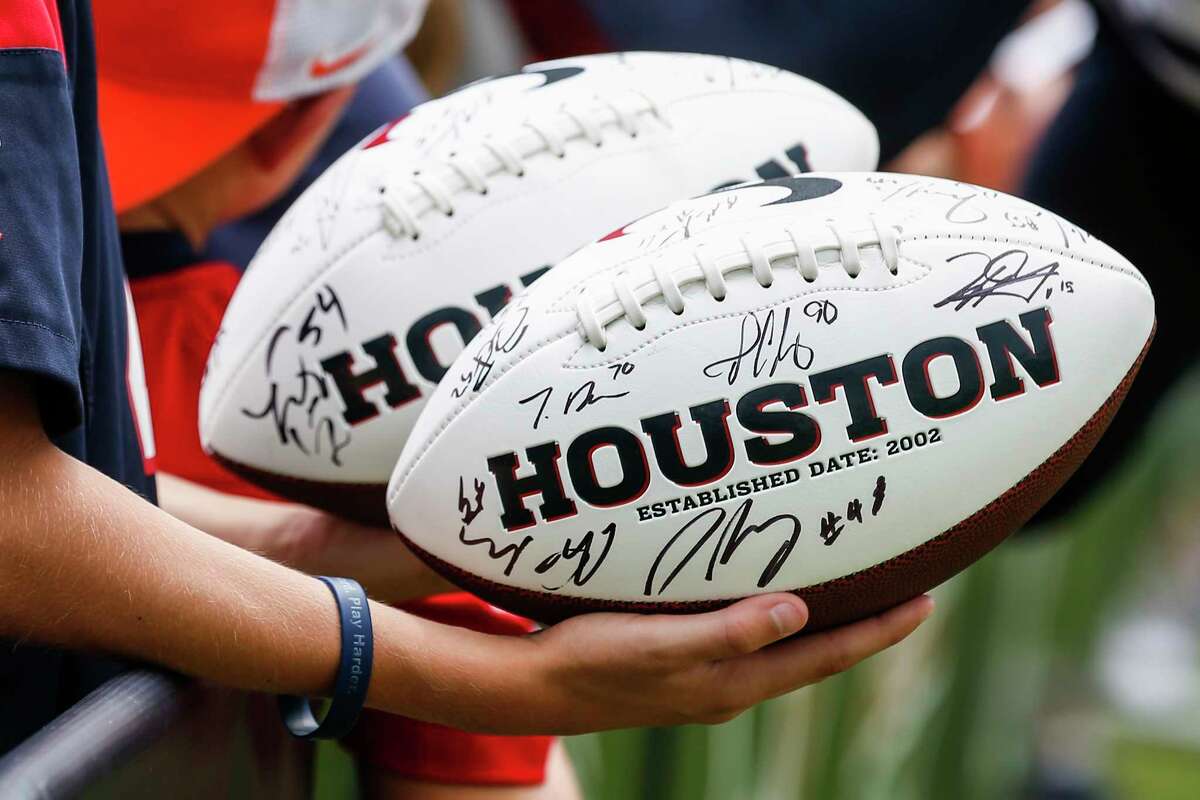 A fan holds autographed Houston Texans footballs during training camp at the Greenbrier Sports Performance Center on Tuesday, July 31, 2018, in White Sulphur Springs, W.Va.