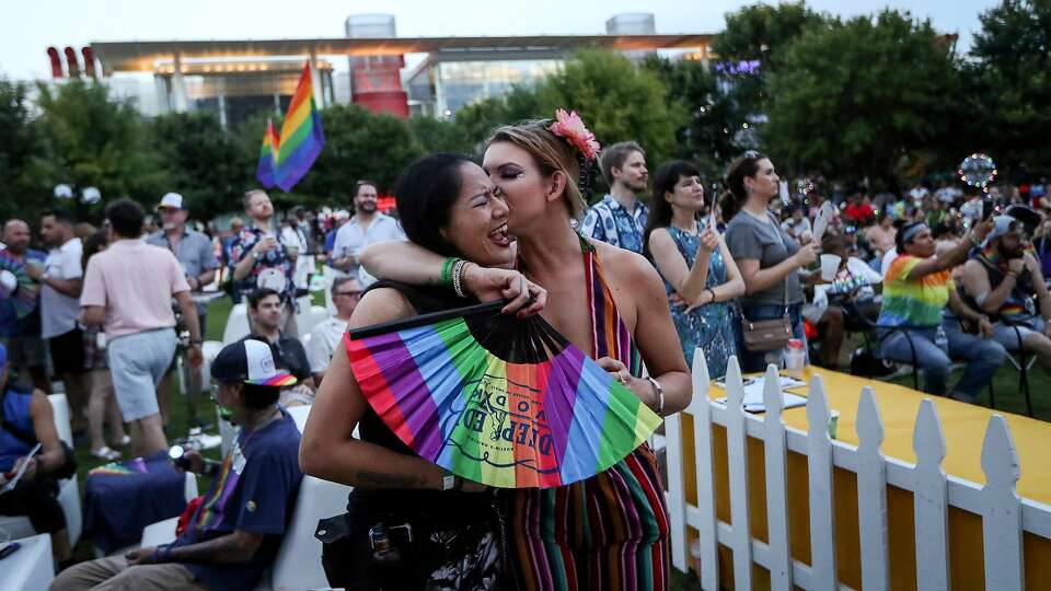 Alana Delarosa sings along to a drag performer as her girlfriend, Nicole Pope, kisses her during a Pride event at Discovery Green on Friday, June 21, 2019, in Houston. 'It's being able to love whoever you want visibly and proudly,' Pope said of Pride festivities.