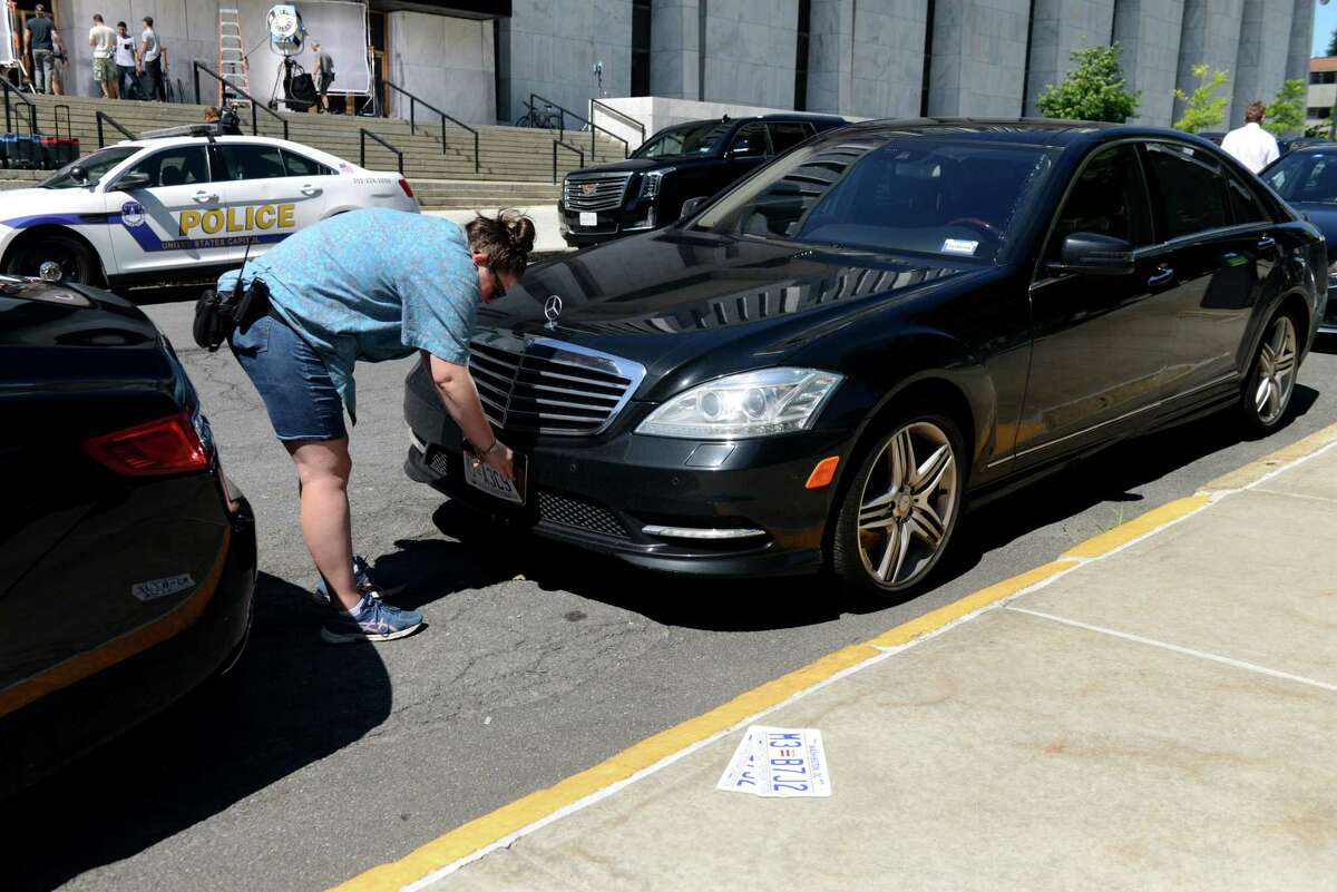 An inspector general's report published March 4, 2021, found widespread issues with the way unmarked plates for political and governmental officials are distributed. Pictured: A production assistant on HBO’s “Succession” removes fake license plates from prop vehicles outside the Legislative Office Building on Monday, July 1, 2019, in Albany, N.Y. (Catherine Rafferty/Times Union)