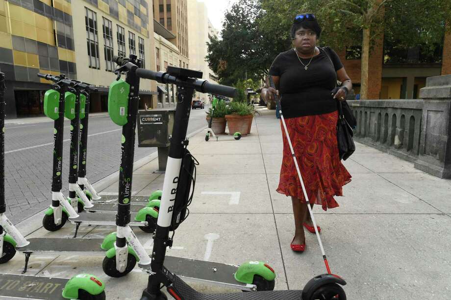 Athalie Malone, who is blind, encounters scooters on a sidewalk along Market Street on the way to a city government meeting. She chairs San Antonio's disability access advisory committee and says she has twice tripped over scooters downtown. Photo: Billy Calzada /Staff Photographer / San Antonio Express-News