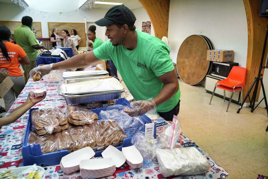 Corry McDonald, volunteer and site supervisor and Keiajah Washington, background, with the Schenectady County Summer Youth Program, serve families food during a SiCM free lunch program at the Greater Faith Christian Center on Tuesday, July 2, 2019, in Schenectady, N.Y. The Schenectady Community Ministries (SiCM), has begun their 25th year of serving summer meals for children. The program feeds children breakfast and lunch at various fixed and mobile sites through August 30th. SiCM is an organization made up of 52 congregations that served 53,150 meals last summer. The locations of the breakfast or lunch sites can be found at www.sicm.us. (Paul Buckowski/Times Union) Photo: Paul Buckowski / (Paul Buckowski/Times Union)