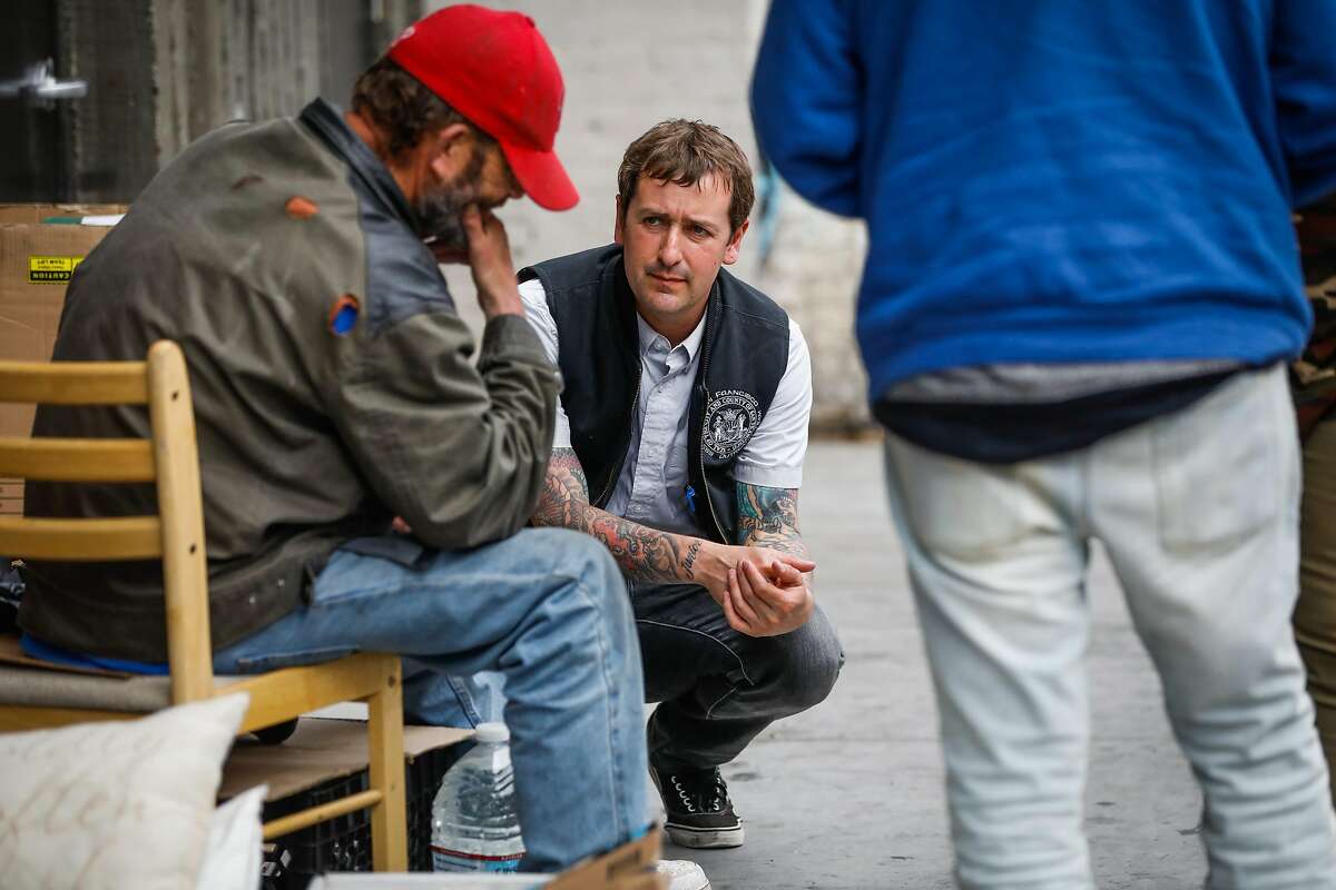 Mark Mazza (center) with the Homeless Outreach Team speaks with a homeless man while doing outreach in the Tenderloin in San Francisco, California, on Wednesday, June 26, 2019.