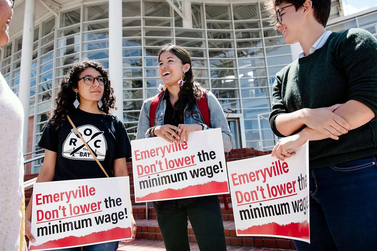 Maricela Gutierrez, left, Maria Moreno, and Hanna Batlan, with the group R.O.C., Restaurant Opportunities Center United, hold signs while joining members of the Service Employees International Union 1021 and other labor activists gather outside City Hall to oppose new wage legislation recently passed by the city council, in Emeryville, CA on June 26th, 2019. The Emeryville City Council in a 3-2 vote passed an ordinance that would create a lower minimum wage for workers at restaurants with 20 or fewer locations globally.