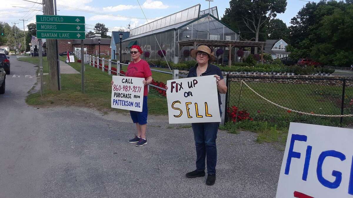 From left, Fran Clem and Jennifer Whittlesey protest in front of an empty Shell gas station owned by Patterson Oil, on Route 202 in Bantam.