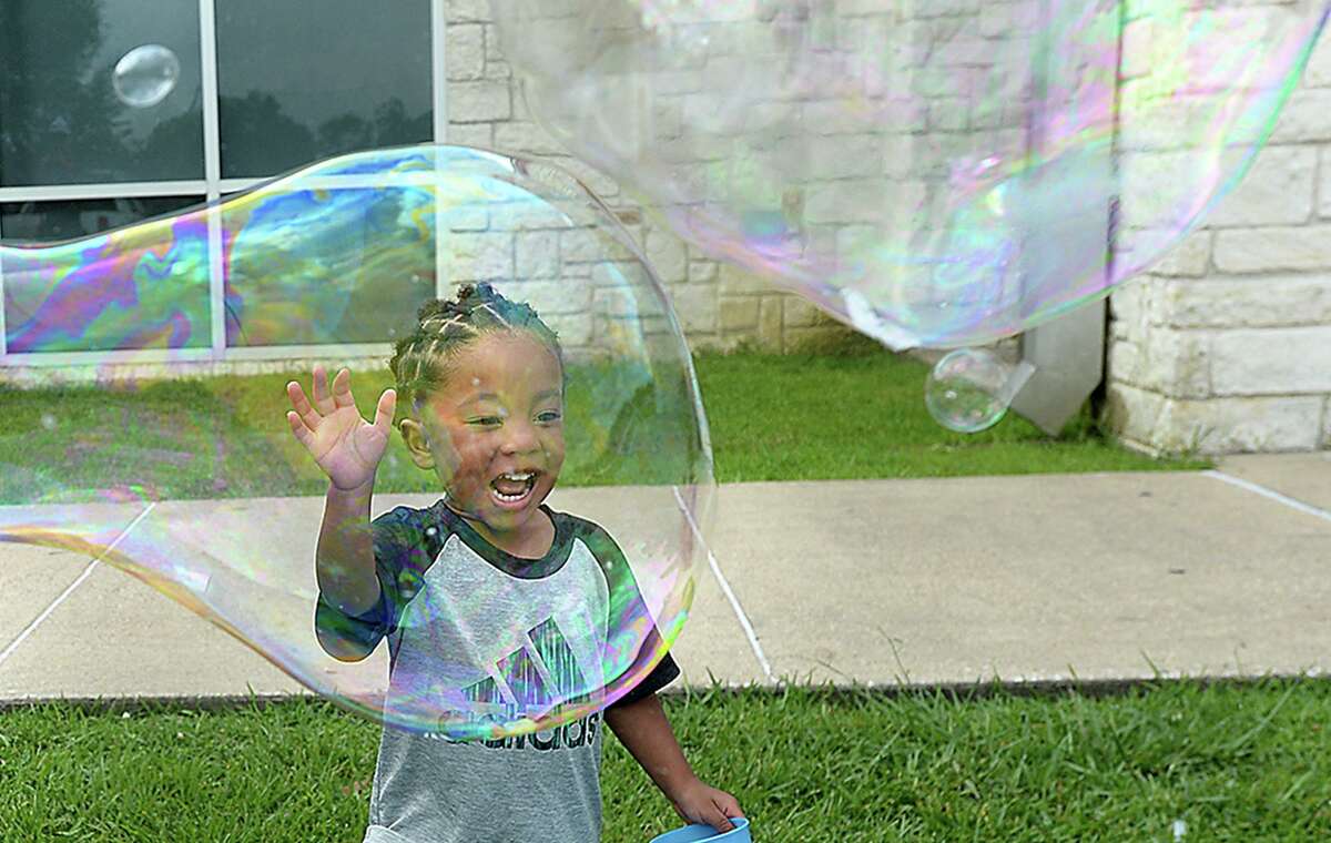 Roman Frank reacts as his mother Asia Perkins creates a large bubble during the Texas Energy Museum and Beaumont Public Library's annual Bubble Day event at the Theodore Johns Library Wednesday. A second event will be held July 10, 11:00 a.m. - 12:30 p.m. at the Rogers Park Community Center. Children and adults can enjoy making large bubbles outdoors, and explore the science of bubbles at various hands-on stations inside. Photo taken Wednesday, June 26, 2019 Kim Brent/The Enterprise