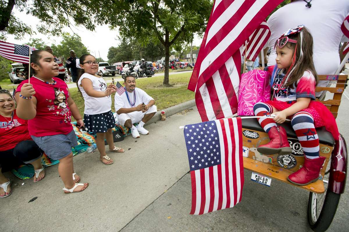 Naomi Mae Sanchez rides on the back of a flag adorned trike as she rides with the E5 Tailgaters in the 20th Annual Lindale Park 4th of July Parade on Thursday, July 4, 2019, in Houston.