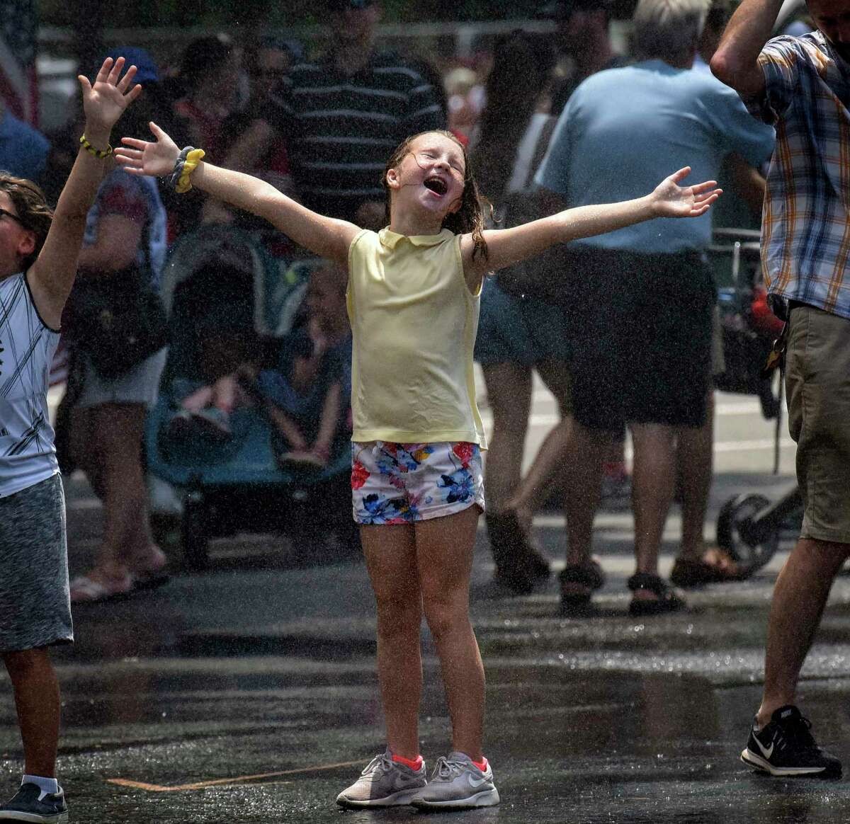 Emily Sheppard, 10, visiting from Richmond, Virginia, exults in the cooling spray provided at the end of the National Independence Day Parade on Thursday.