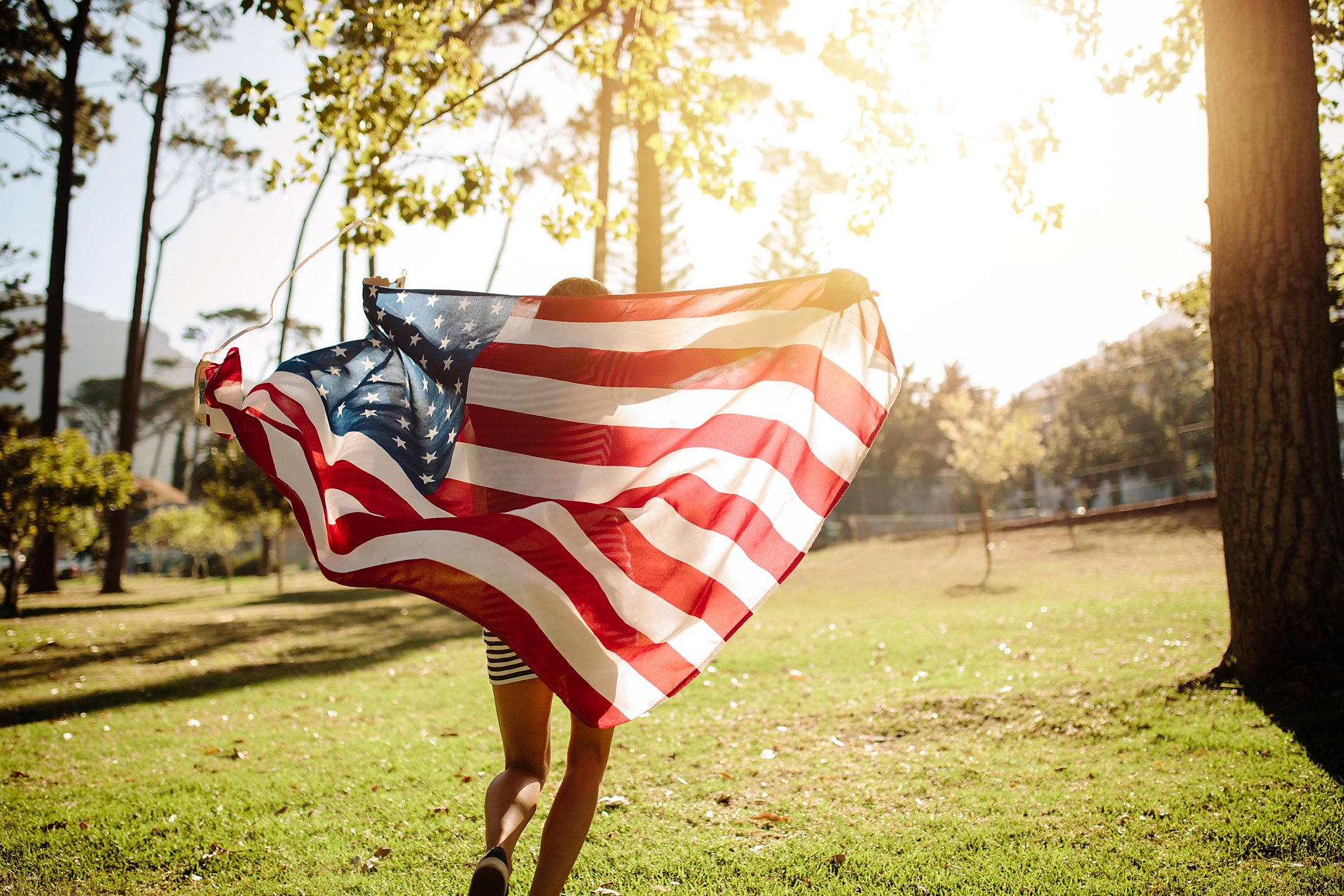 Fly flags. Девушка с американским флагом. Бежит с флагом. Американец с флагом. Парк с флагами.