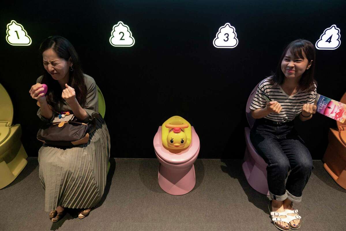 In this Tuesday, June 18, 2019, photo, two women jokingly motion to give a push while sitting on colorful toilet bowls at the Unko Museum in Yokohama, south of Tokyo. In a country known for its cult of cute, even poop is not an exception. A pop-up exhibition at the Unko Museum in the port city of Yokohama is all about unko, a Japanese word for poop. The poop installations there get their cutest makeovers. They come in the shape of soft cream, or cupcake toppings. (AP Photo/Jae C. Hong)