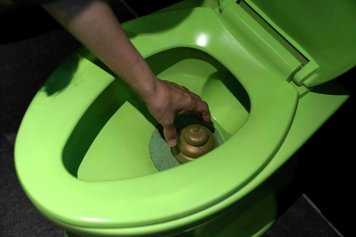 In this Tuesday, June 18, 2019, photo, a visitor reaches into a toilet bowl to pick up a toy poop at the Unko Museum in Yokohama, south of Tokyo. In a country known for its cult of cute, even poop is not an exception. A pop-up exhibition at the Unko Museum in the port city of Yokohama is all about unko, a Japanese word for poop. The poop installations there get their cutest makeovers. They come in the shape of soft cream, or cupcake toppings. (AP Photo/Jae C. Hong)