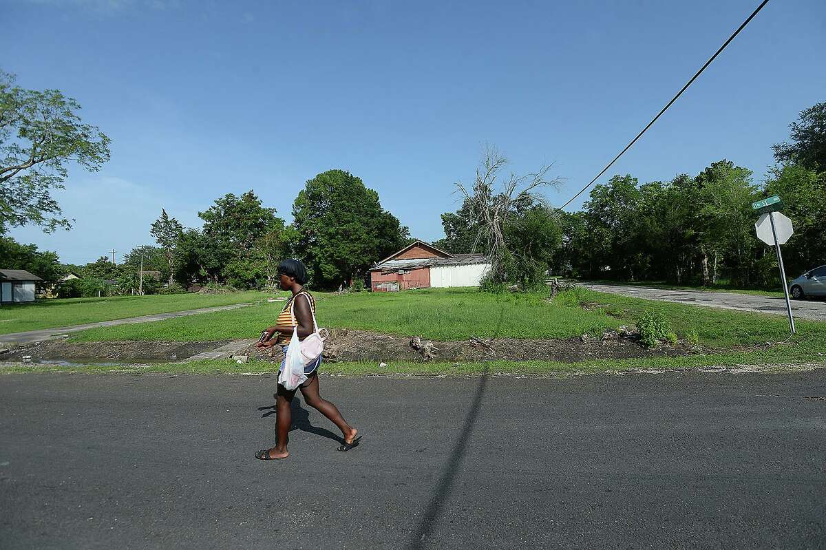 A woman walks past an empty lot that used to have three houses sits at the corner of Vicksburg and 11th Streets in Port Arthur, which is concerned that its population decline, that saw a further decrease in the wake of Tropical Storm Harvey, will dip below 50,000. The low population level could effect city funding. Photo taken Wednesday, July 3, 2019 Kim Brent/The Enterprise