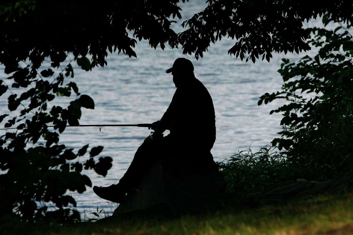 Kenny Dykes of Alexandria, Va., fishes in the Potomac River next to the George Washington Memorial Parkway (not pictured) in Arlington, Va. on Monday July 7, 2008. Meandering through wooded hills, the George Washington Memorial Parkway offers stunning views of the Potomac River and the capital's monuments beyond. It also offers one of the most direct commutes to downtown Washington for suburban residents, and that has brought traffic it was never intended to handle. (AP Photo/Jacquelyn Martin)