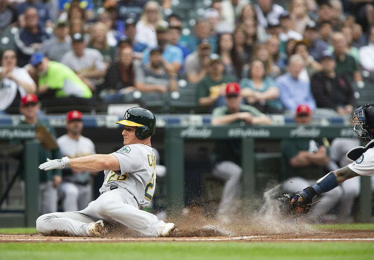 Oakland Athletics' Matt Chapman slides safely into home to score, avoiding the tag by Seattle Mariners catcher Omar Narvaez during the first inning in a baseball game Saturday, July 6, 2019, in Seattle. (AP Photo/Lindsey Wasson)