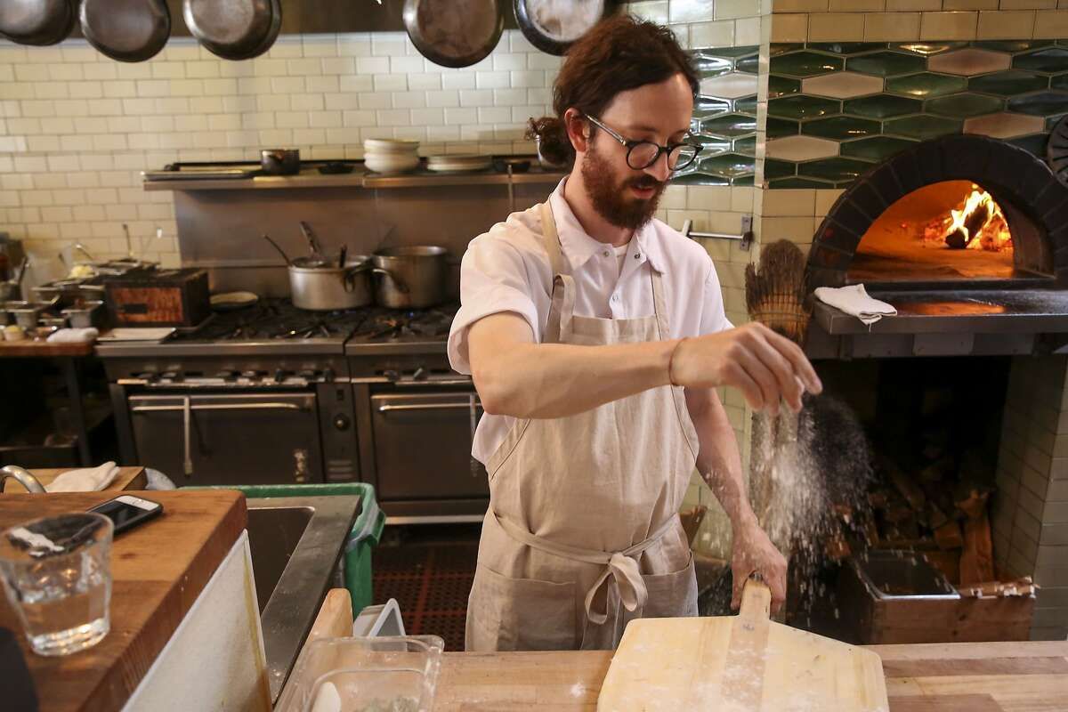 Chef Martin Salata sprinkles a wooden pizza paddle as he makes pizza at Boot & Shoe Service Thursday, June 27, 2019, in Oakland, Calif. A year after new owners Jen Cremer and Richard Clark bought Boot & Shoe Service from Charlie Hallowell, they are unveiling a new name for the restaurant: Sister. The new name is part of the rebranding of the restaurant?•s feel, workplace culture and menu.