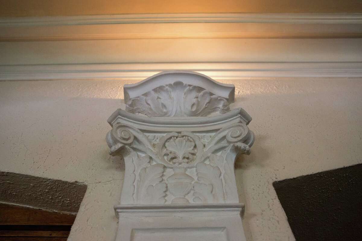 One of the original details that remain in the living area include four vertical friezes, two flanking the fireplace and two book-ending the opposing window. All are topped with lighted sconces, although only the two on the fireplace side work.