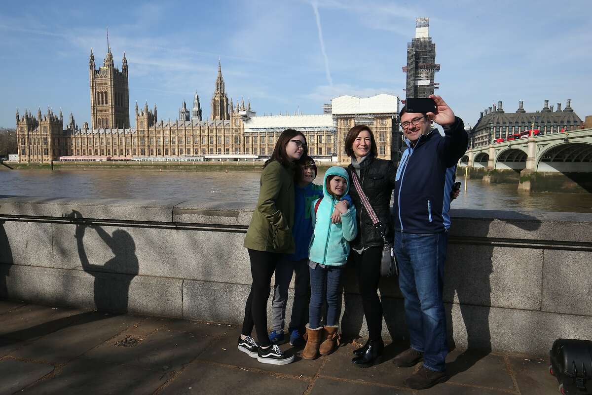 Tourists take a selfie with the Houses of Parliament from across the River Thames on the Southbank in London. (Photo by Jonathan Brady/PA Images via Getty Images)