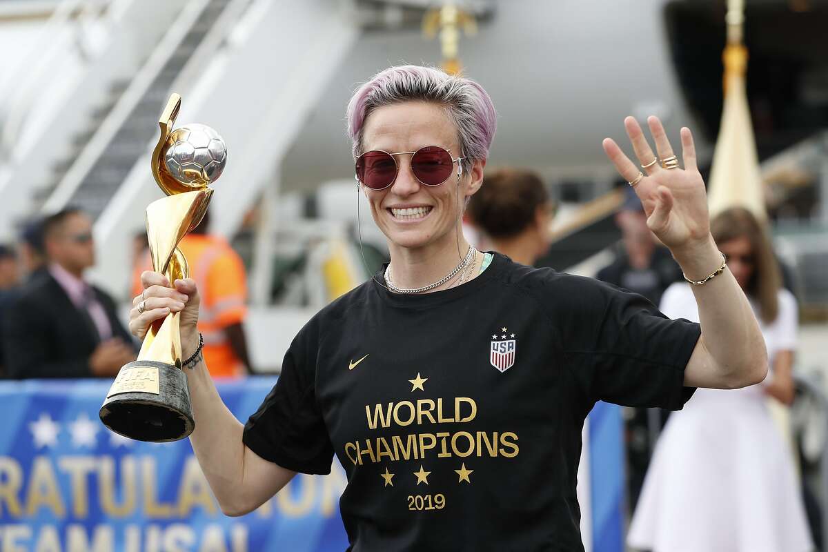 United States women's soccer team member Megan Rapinoe holds the Women's World Cup trophy as she celebrates in front of the media after arriving at Newark Liberty International Airport, Monday, July 8, 2019, in Newark, N.J. (AP Photo/Kathy Willens)