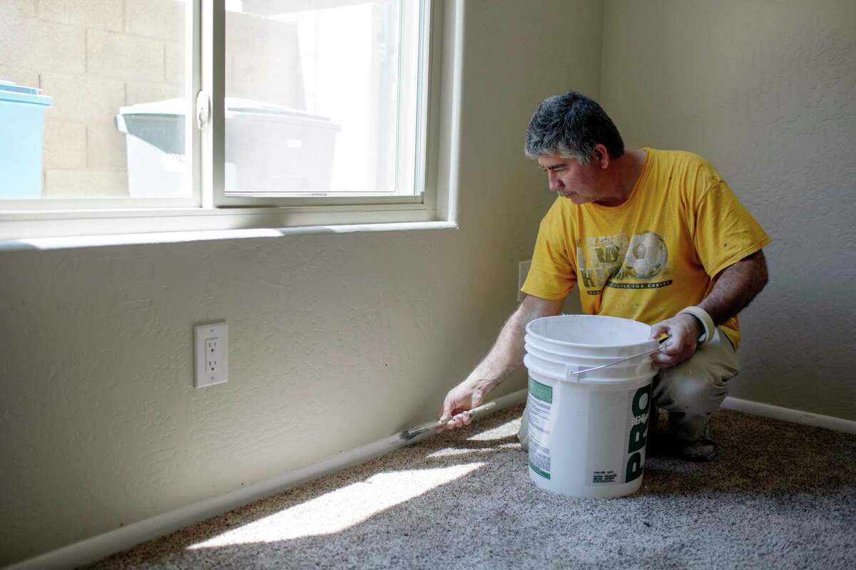 Eddy Gomez paints trim in a house that Zillow bought for resale in Phoenix, Ariz. The company sends crews to paint, carpet and landscape recently purchased properties so they can be put back on the market quickly. (Caitlin O'Hara/The New York Times)
