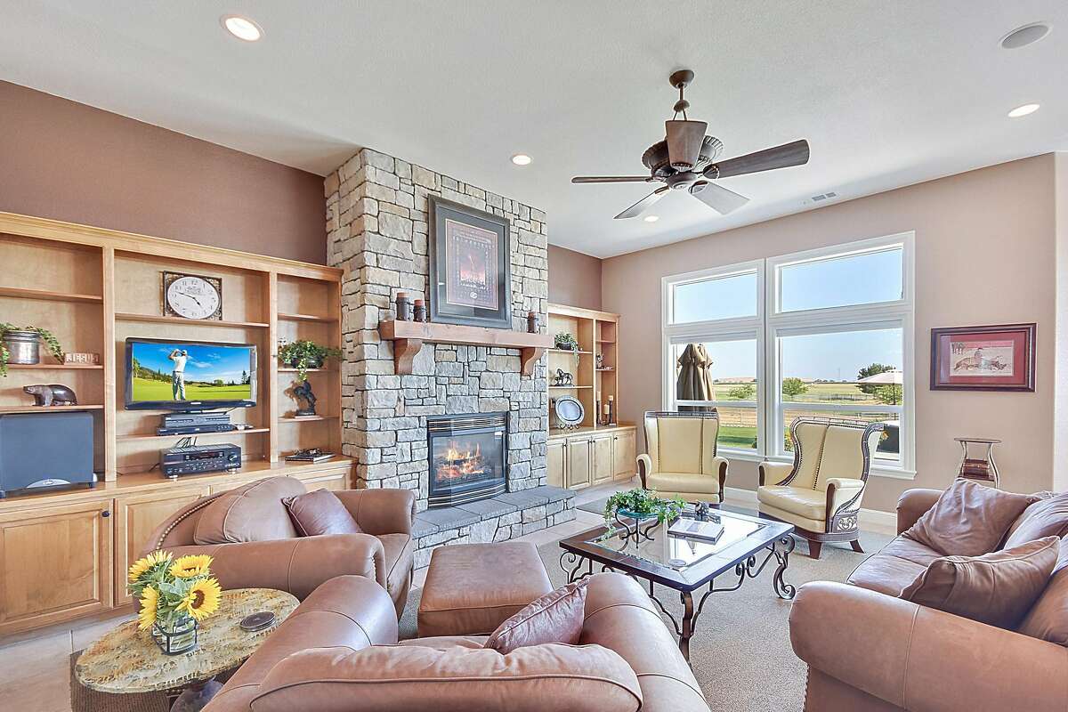 A gas fireplace rests within a stone surround stretching from floor to ceiling and warms the living room of 15944 E. Kettleman Lane in Lodi.