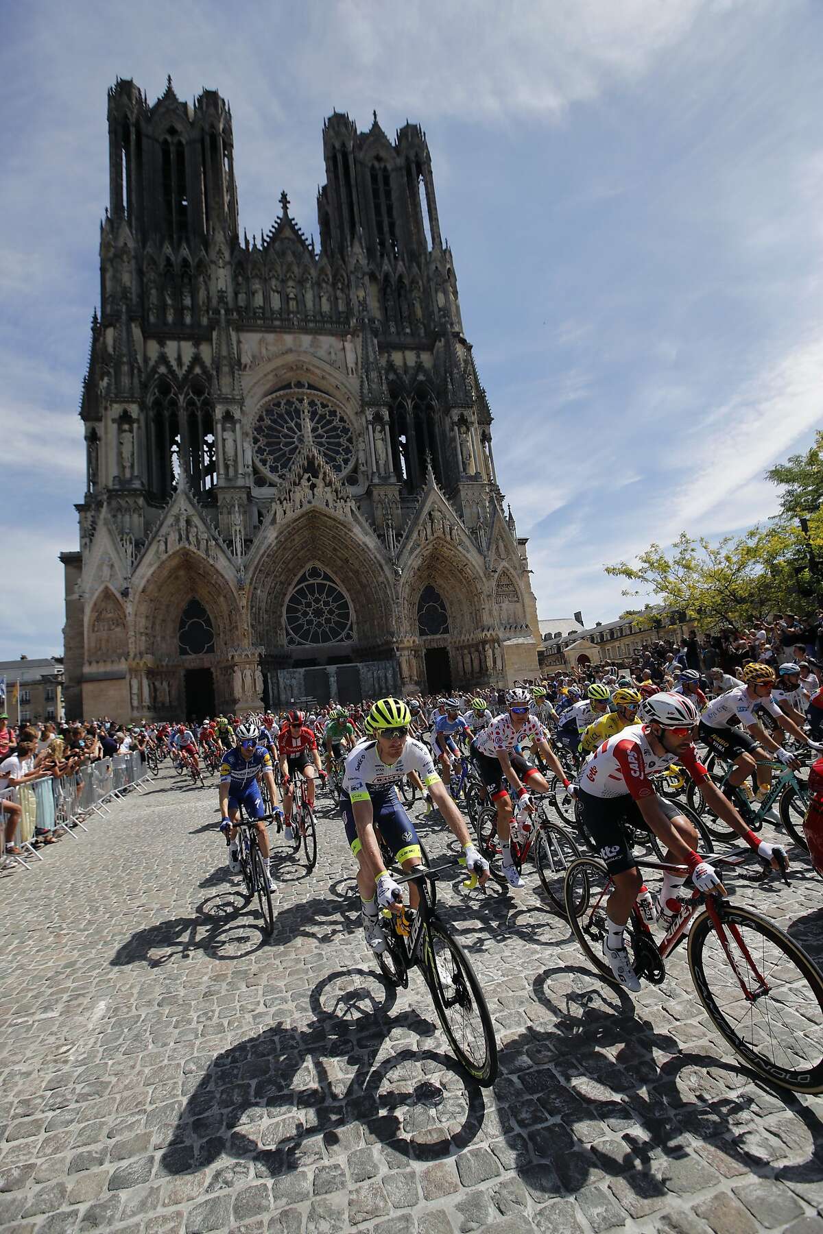 The pack rides by the Reims cathedral during the fourth stage of the Tour de France cycling race over 214 kilometers (133 miles) with start in Reims and finish in Nancy, France, Tuesday, July 9, 2019. (AP Photo/Christophe Ena)