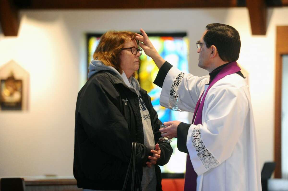 Msgr. Kevin Royal places ashes on a congregants head during Ash Wednesday inside the Church of the Holy Spirit on Scofieldtown Road in Stamford on Wednesday, Feb. 14, 2018.