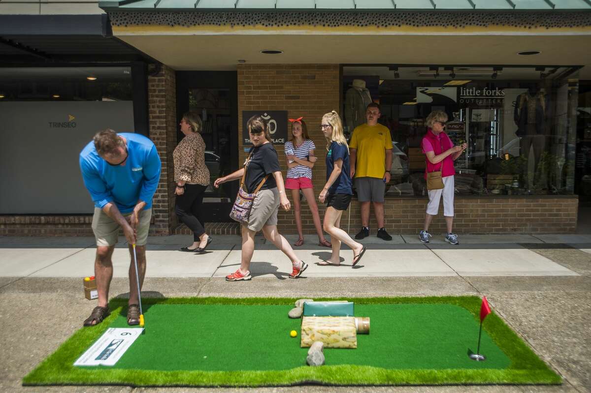 Craig Lash of Novi, left, plays mini golf on Wednesday, July 10, 2019 in downtown Midland during Mini Golf on Main, an event hosted by the Midland Downtown Business Association, which will continue through Saturday, July 13. (Katy Kildee/kkildee@mdn.net)