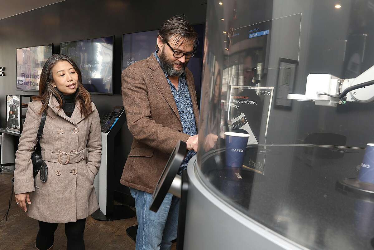 Dwayne (cq) and his wife Sandy Lythgo from Singapore have a robot made Flat White coffee at Cafe X on Friday, March 8, 2019, in San Francisco, Calif.