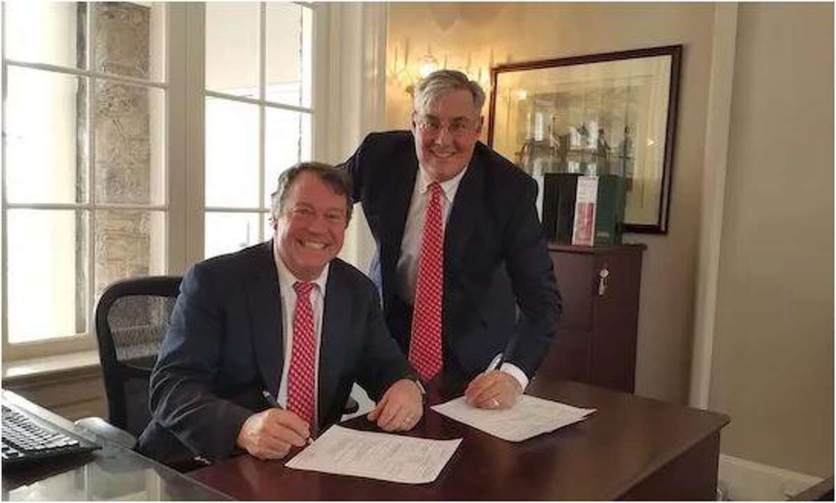 Larry Curry, director of facilities at Ridgefield Academy, and the school's CFO Briggs Tobin signed a deal for the recently installed solar panels.