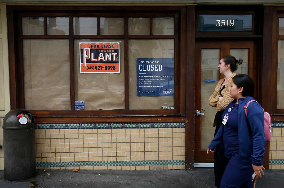 Pedestrians stroll past the vacant storefront where Noah’s Bagels was located in the Laurel Village shopping district in San Francisco, Calif. on Thursday, July 11, 2019. Several businesses along the strip on California Street have suddenly shut their doors for good.