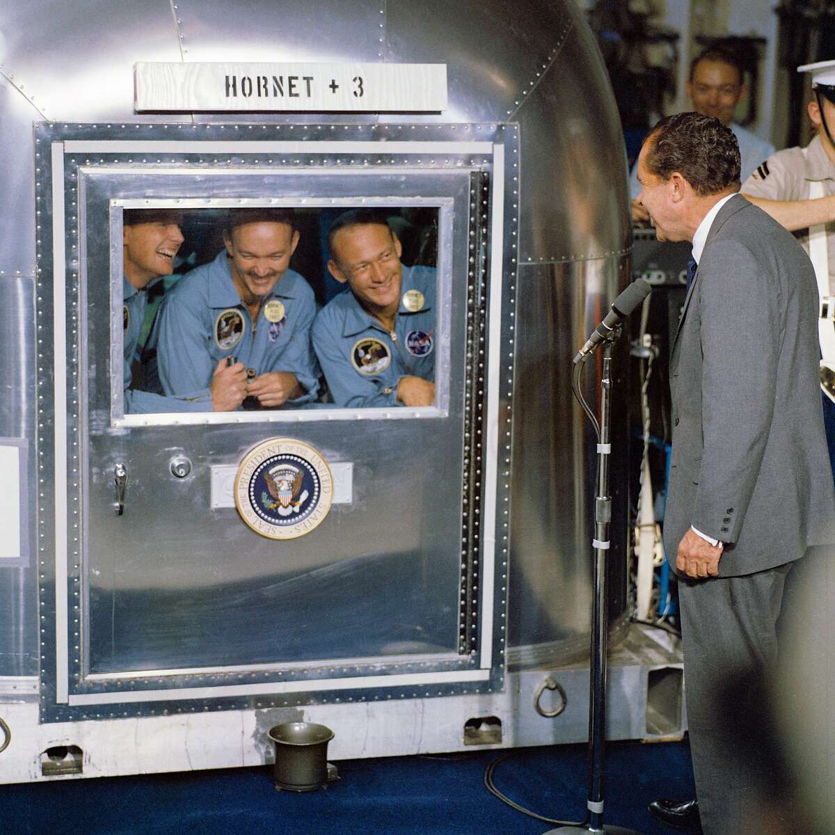 (1969年7月24日)——美国总统理查德·尼克松(Richard M. Nixon)在太平洋中部回收区欢迎阿波罗11号宇航员乘坐“大黄蜂”号飞船，这是历史性的阿波罗11号登月任务的主要回收船。已经被限制在流动隔离设施(MQF)的是(从左至右)指挥官尼尔·a·阿姆斯特朗;迈克尔·柯林斯，指令舱飞行员;以及登月舱飞行员小埃德温·e·奥尔德林。阿波罗11号于1969年7月24日上午11点49分(CDT)溅落在夏威夷西南约812海里处，距离美国大黄蜂号只有12海里。这三名宇航员将留在MQF，直到他们到达载人航天中心(MSC)月球接收实验室(LRL)。当宇航员阿姆斯特朗和奥尔德林在登月舱降落时，“鹰”号探索月球宁静海地区时，宇航员柯林斯留在了指挥与服务舱(CSM)在月球轨道上的哥伦比亚号。图片来源:NASA