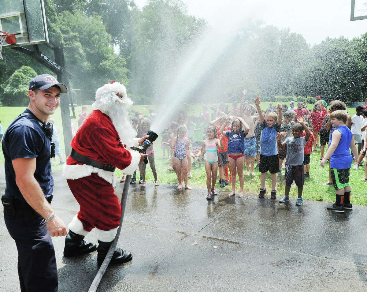 With a blast of water from a hose, Santa cools off campers during the annual Boys & Girls Club of Greenwich Christmas in July event, courtesy of the Greenwich Fire Department, at Camp Simmons, Greenwich, Conn., Friday, July 27, 2018.