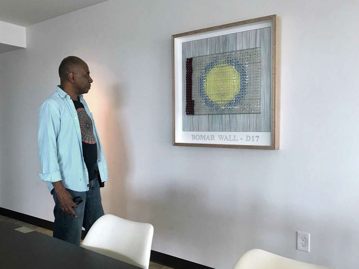 Artist Selven O'Keef Jarmon looks at one of his assemblages incorporating unused panels from his "360 Degrees Vanishing" project. This drawing is on display in a meeting room at the Mid-Main Lofts..