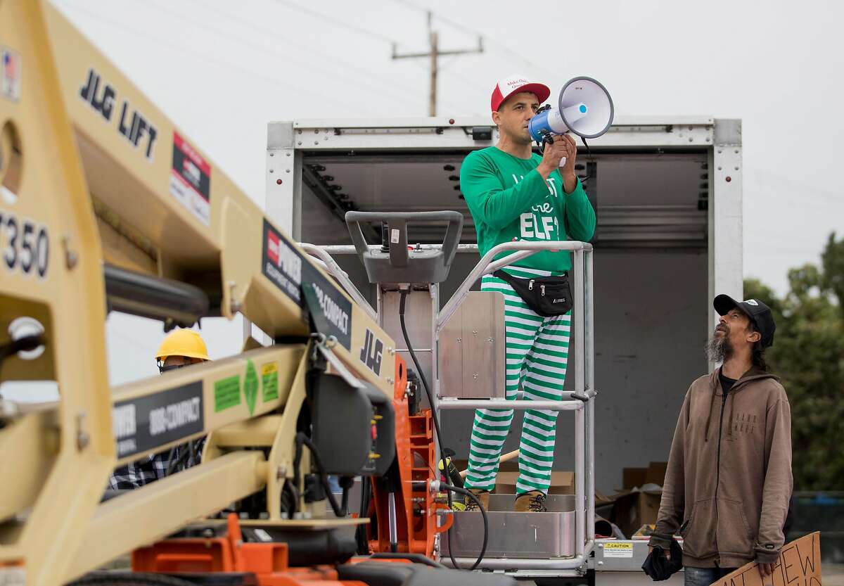 Encampment resident Oz (right) confronts Oakland landlord Gene Gorelik as he stands on a boom lift with a megaphone during a demonstration held at a homeless encampment along Alameda Avenue behind Home Depot in Oakland, Calif. Friday, July 12, 2019. Gorelik, a real estate developer previously sued by the city, rented the boom lift to offered money to residents of a homeless encampment if they leave.