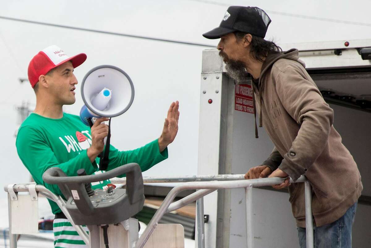 Homeless encampment resident Oz (right) confronts Oakland landlord Gene Gorelik as he stands on a boom lift with a megaphone during a demonstration held at a homeless encampment along Alameda Avenue behind Home Depot in Oakland, Calif. Friday, July 12, 2019. Gorelik, a real estate developer previously sued by the city, rented the boom lift to offered money to residents of a homeless encampment if they leave.