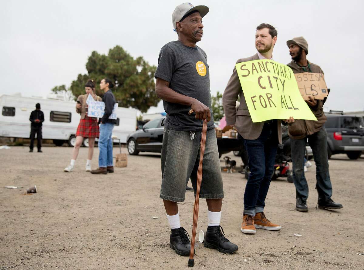 Encampment resident Curtis James stands with advocates during a protest held at a homeless encampment behind Home Depot in Oakland, Calif. Friday, July 12, 2019. Gene Gorelik, a real estate developer previously sued by the city, held a large demonstration, rented a boom lift and offered money to residents of a homeless encampment if they leave.