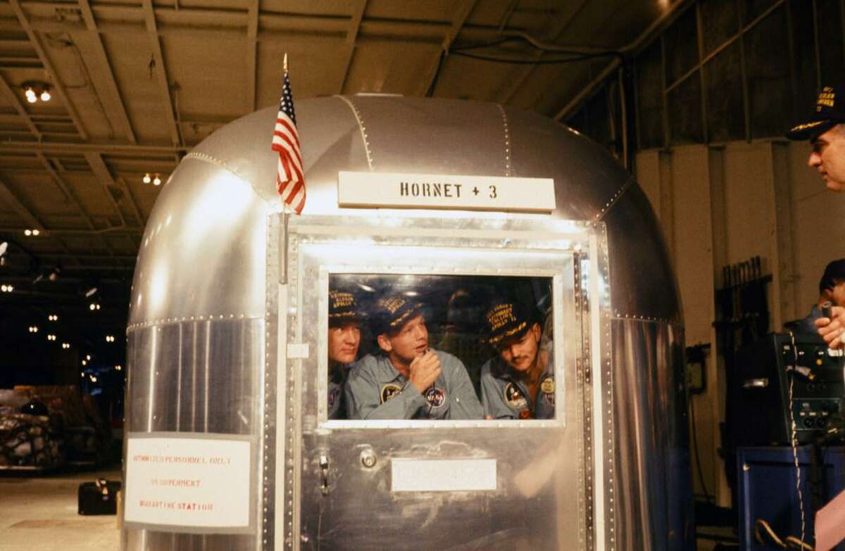 Apollo 11 astronauts Edwin Aldrin, Jr., left, Neil Armstrong, and Michael Collins are seen in quarantine in the Mobile Quarantine Facility as they are transported from the Pacific Ocean to Johnson Space Center in Houston.