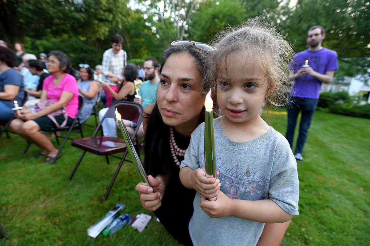 Massiel Zucco-Himmelstein of Stamford and her daughter Ava Himmelstein participate in a candle lighting ceremony during a Lights for Liberty vigil at the North Stamford Community Church in North Stamford on Friday.
