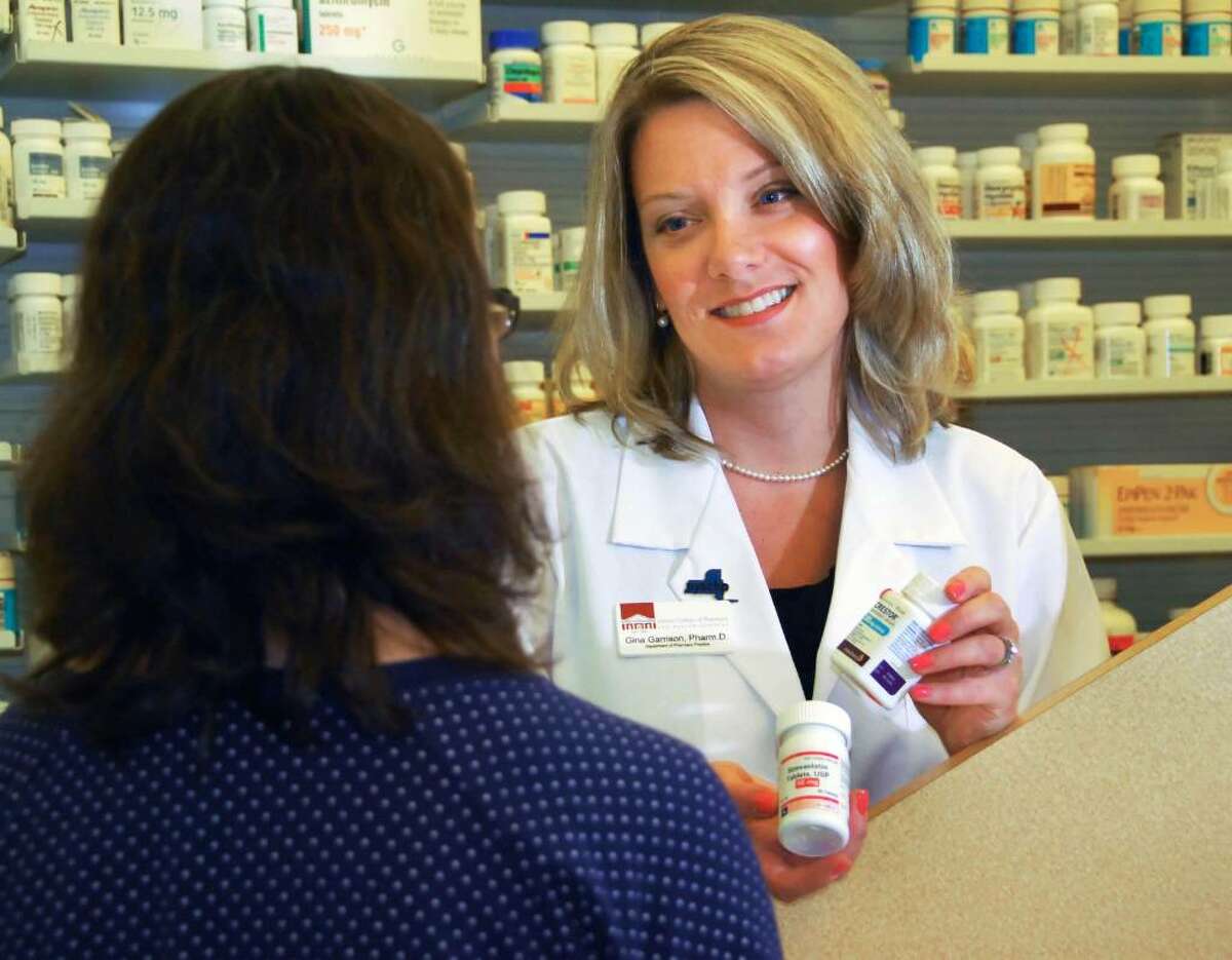 Albany College of Pharmacy and Health Sciences Associate Professor Gina Garrison, at right, displays generic and brand-name cholesterol control drugs like Lipitor, Crestor, and the generic, simvastatin at the college Friday. (John Carl D'Annibale / Times Union)