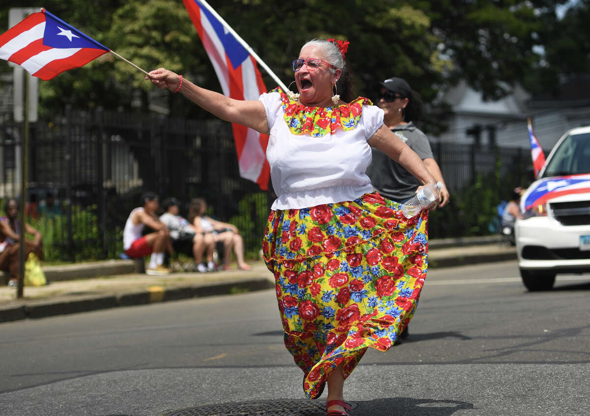 Milagros Ortiz, of New Britain, dances her way down Park Avenue during the annual Puerto Rican Day Parade in Bridgeport, Conn. on Sunday, July 14, 2019.