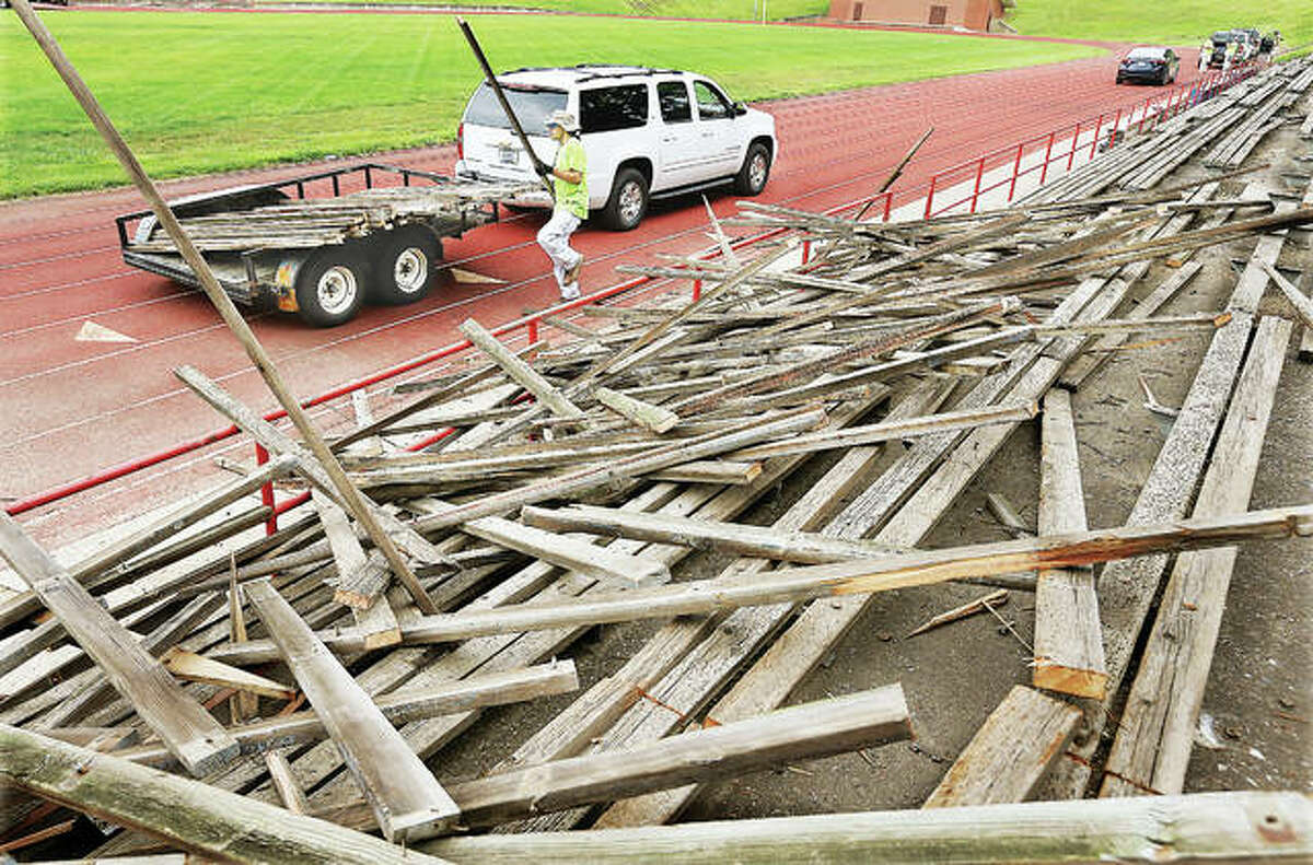 A construction worker on Monday stacks 2-by-4-inch boards removed from the visitors side bleachers in Alton’s Public School Stadium. The previous bleachers, on both sides of the football field, were wood and covered with a vinyl-type of outer skin to make them smoother. The former red, white and blue bleachers are being replaced with a new aluminum seated structure.