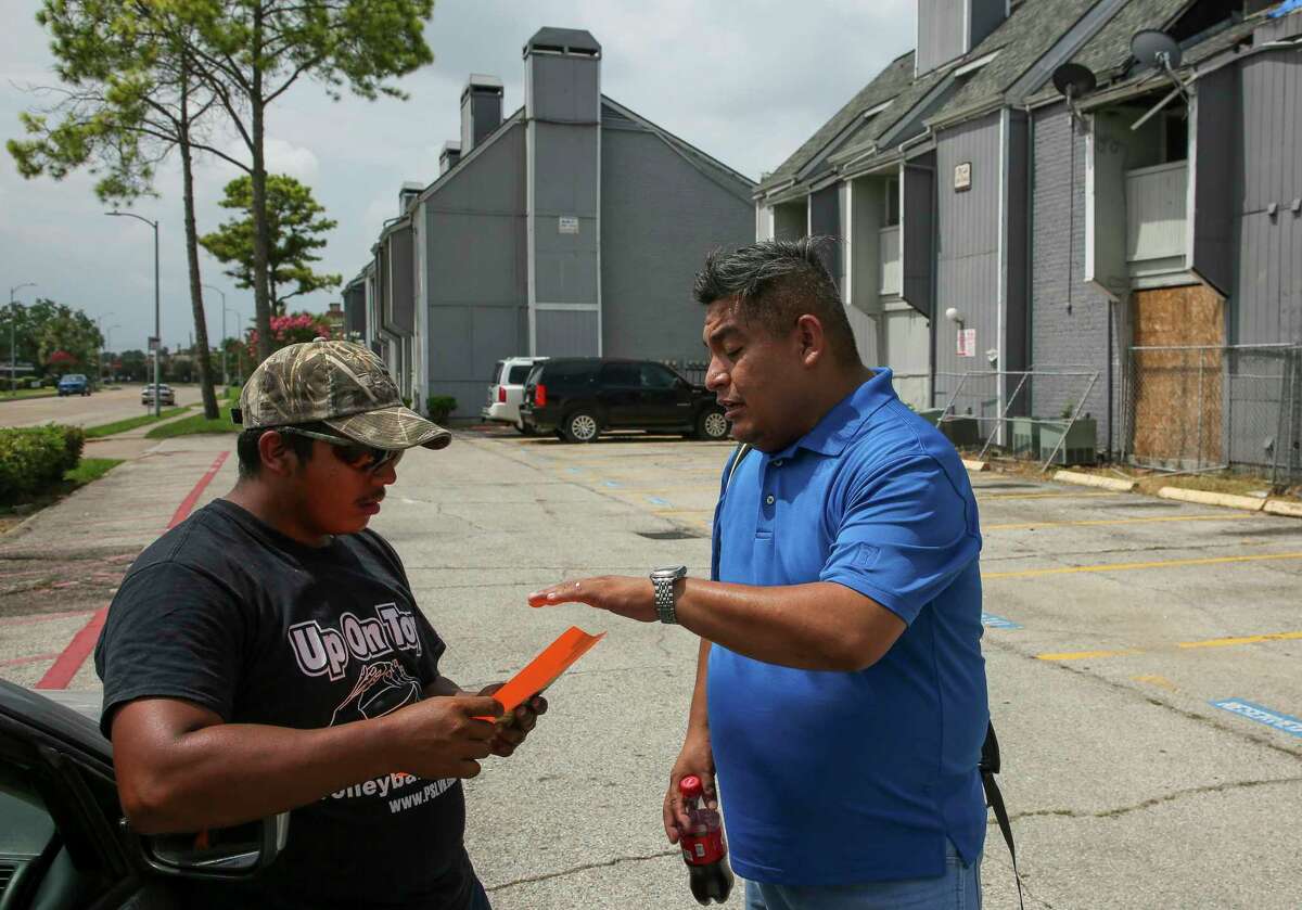 FIEL organizer Alain Cisneros, right, hands out a "Know Your Rights" pamphlet to a man outside the El Paraiso Apartments complex Monday, July 15, 2019, in Houston. ICE agents conducted a raid at the complex early Monday morning.