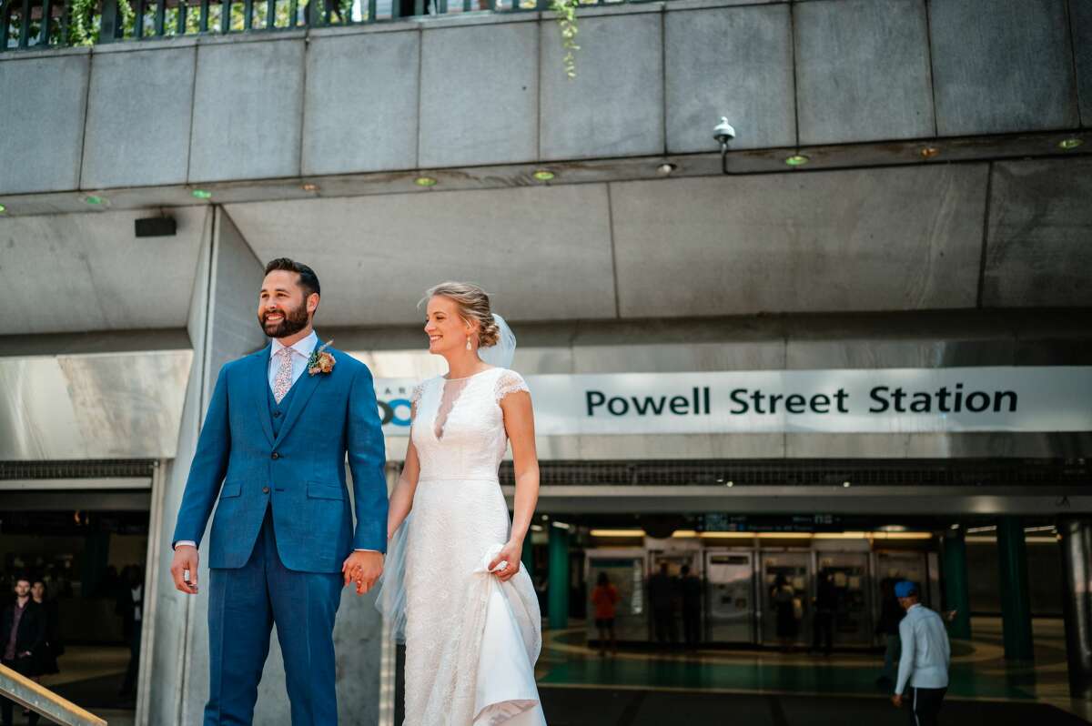 Laura Hansen and Jeremy Bachrach stand outside the Powell Street BART station on the wedding day. The couple opted for public transit for their special day over a limousine or party bus.