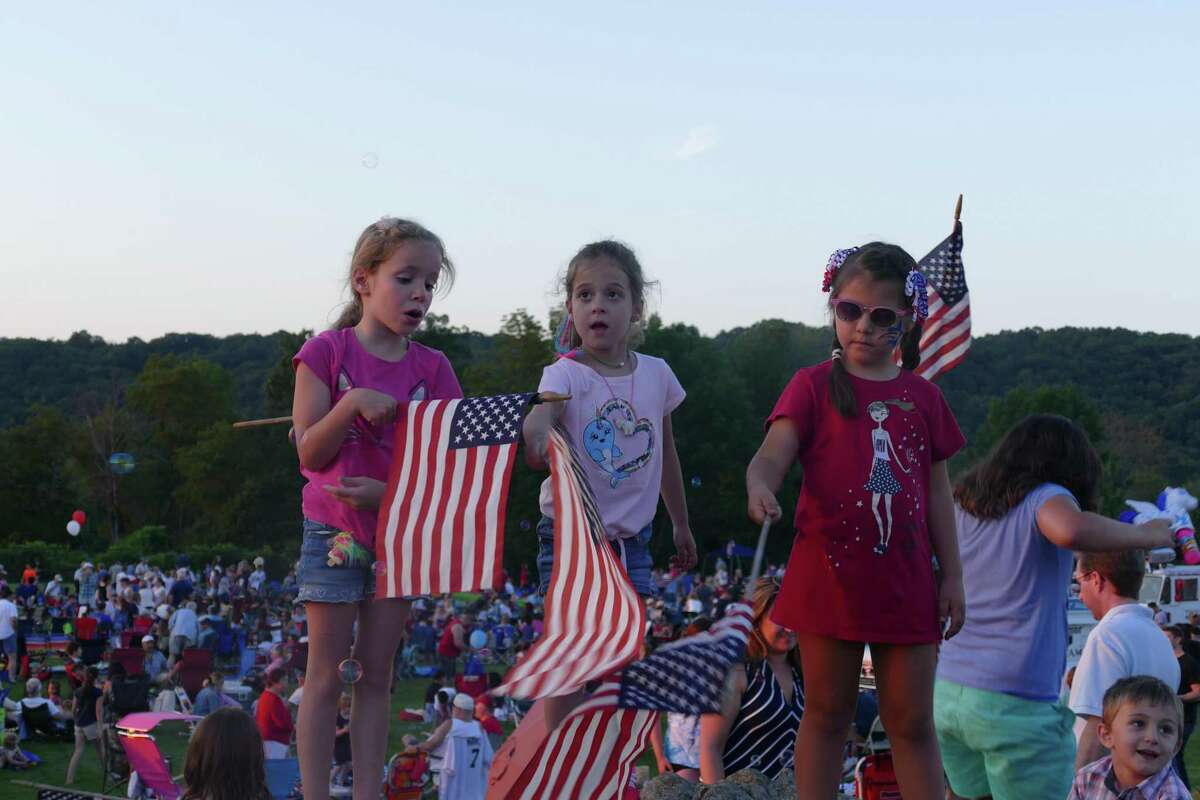 From left to right: Emma, Camila, and Ali wave the American flag during the town's annual Fourth of July celebration at Ridgefield High School last week.