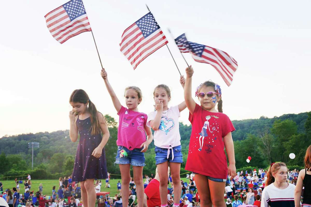 From left to right: Emma, Camila, and Ali wave the American flag during the town’s annual Fourth of July celebration at Ridgefield High School last week.