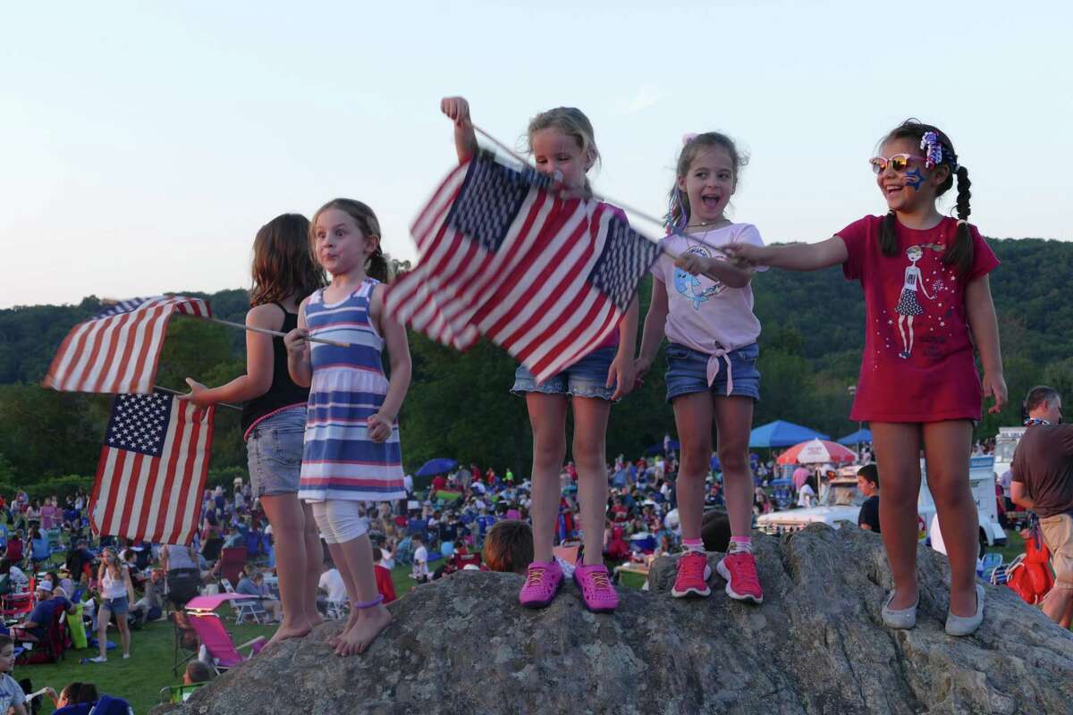 From left to right: Emma, Camila, and Ali wave the American flag during the town's annual Fourth of July celebration at Ridgefield High School last week.