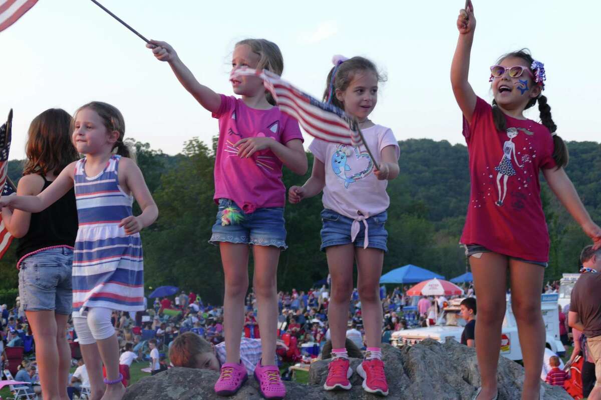 From left to right: Emma, Camila, and Ali wave the American flag during the town's annual Fourth of July celebration at Ridgefield High School last week.