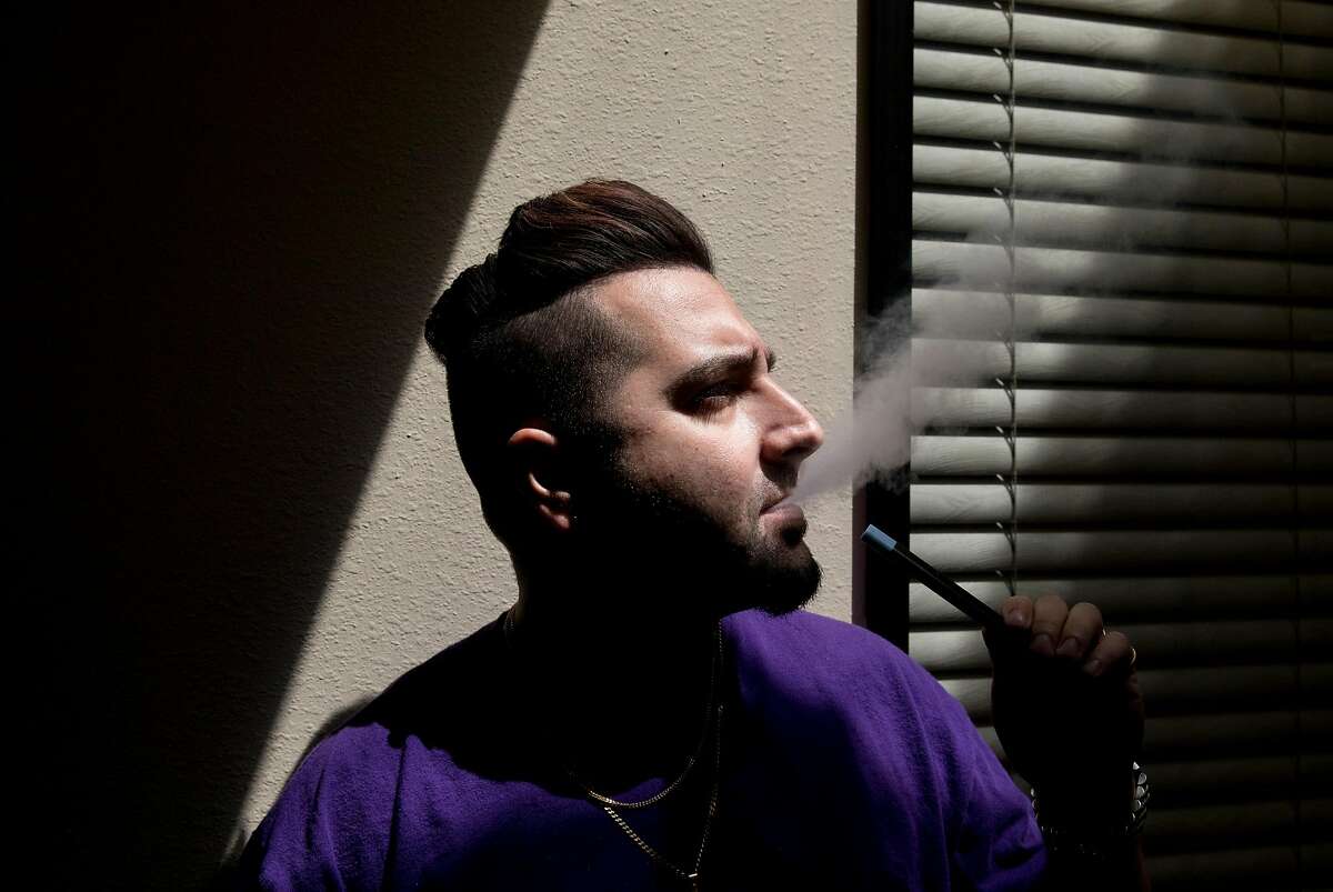 Customer service manager Cyrus Malekzadeh smokes a vape inside Apollo ECigs in Livermore, Calif. Tuesday, July 16, 2019.